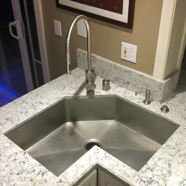 Stainless steel custom single bowl corner sink with Waterstone faucet suite.