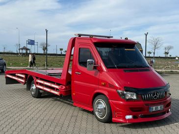 Sleek red tow truck parked on a paved area with a clear sky.