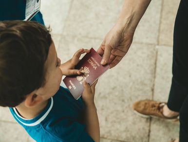 A child receiving a Spanish passport from an adult in a travel setting.