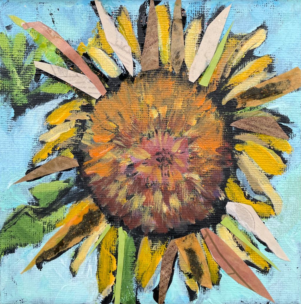 A close up of a large sunflower against a blue sky.