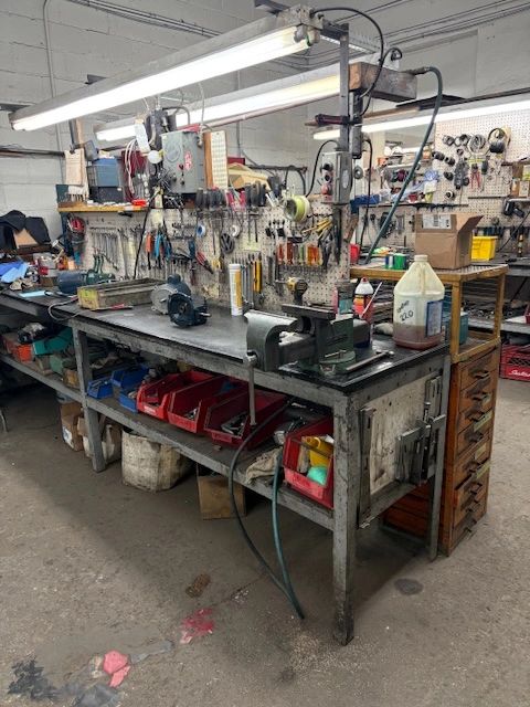 Banc d'atelier avec outils suspendus et rangements rouges.