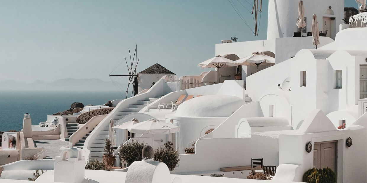 White buildings and windmills overlooking the sea in a Mediterranean setting.
