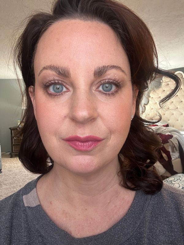 A woman with blue eyes and curled hair wearing makeup.