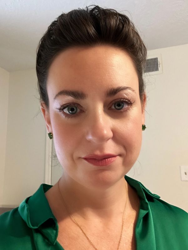 Woman with dark hair and green blouse looking at the camera.