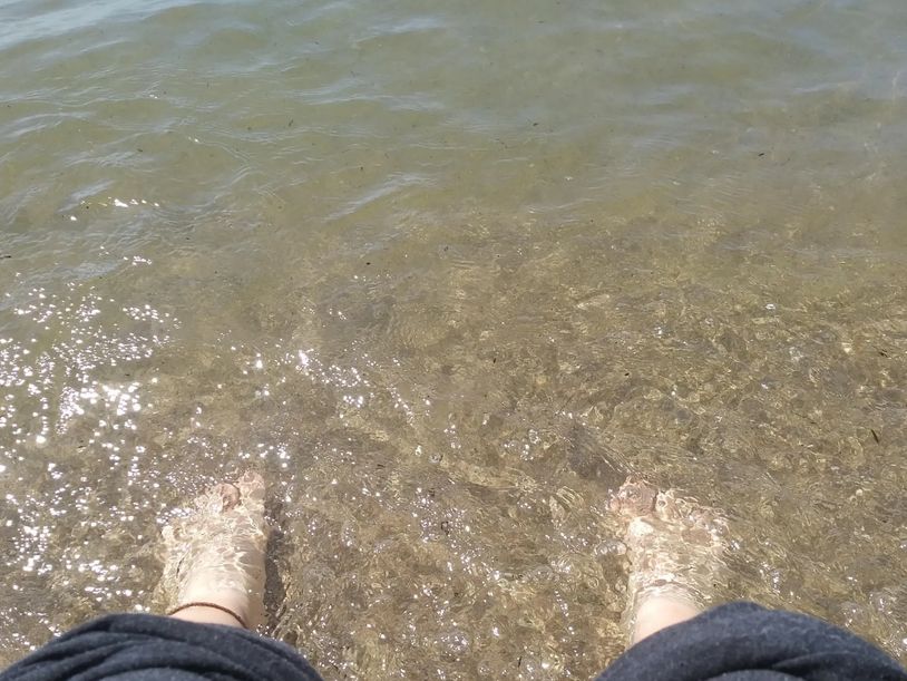 Feet standing in calm water representing grounding, embodiment, and somatic therapy for adults in On