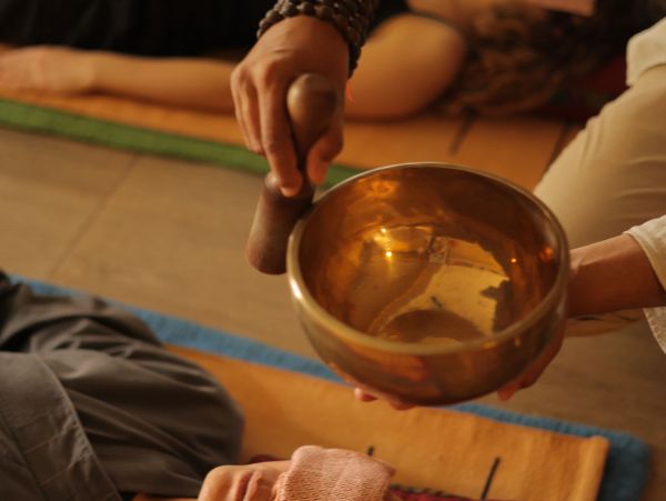 Person using a Tibetan singing bowl during a healing session.
