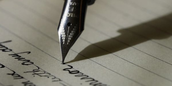 Pen tip writing on lined paper, script writing, shadow.