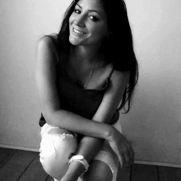 Smiling woman sitting casually, looking at the camera in a black and white photo.