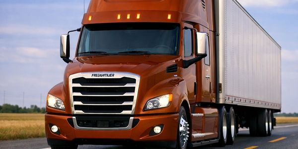 A bright orange Freightliner semi-truck on the road.