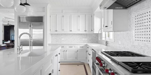 Bright white kitchen with marble countertops and stainless steel appliances.