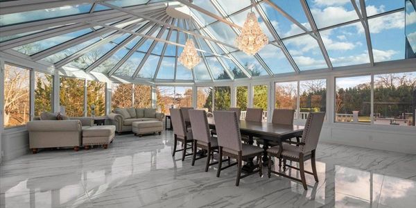 Spacious sunroom with glass ceiling, modern dining set, and cozy seating area.