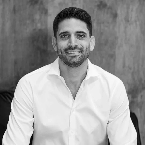 Smiling man in a white shirt against a textured background.