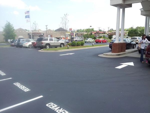 Parking lot with reserved spaces and a woman near a vehicle.