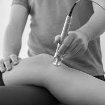Chiropractor performing laser therapy to a patient's knee. 