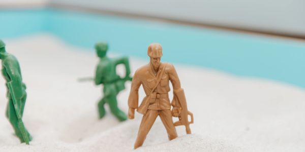 Toy soldiers in sand representing a battle.