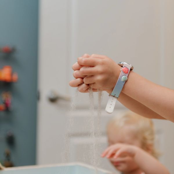 Child playing with sand falling through hands indoors.