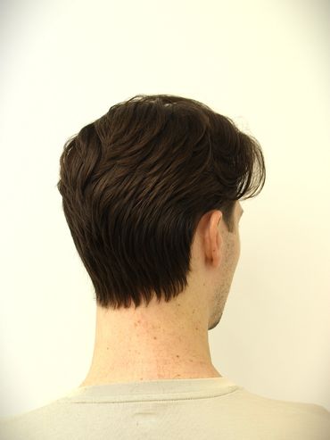 Back view of a man with neatly styled dark brown hair against a plain background.