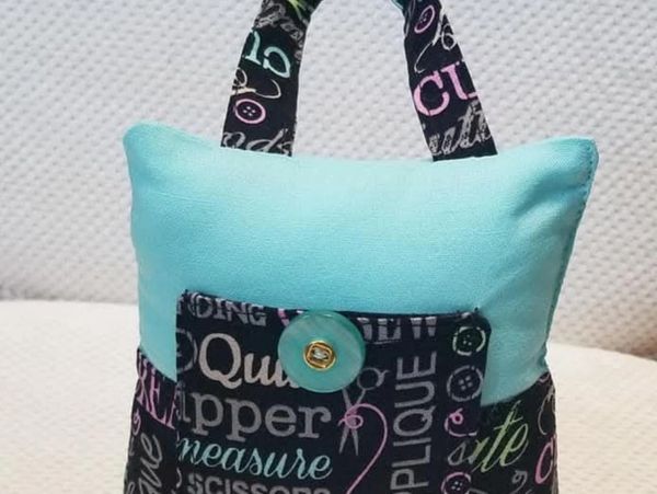 Small fabric doorstop with button and word print design.