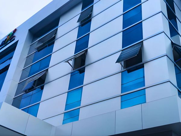 Modern building facade with alternating blue glass and white panels, some windows open.