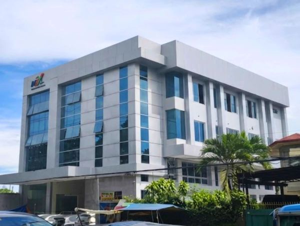 Modern white office building with large glass windows under a blue sky.