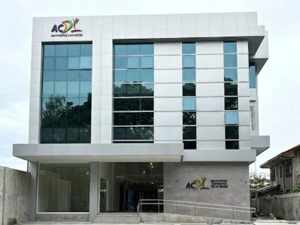 Modern office building with reflective glass windows and a ramp entrance.