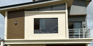 Modern two-story house with large windows and balcony.
