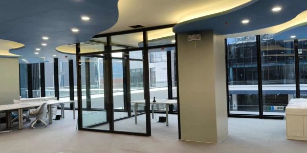 Modern office space with glass partitions and stylish ceiling design.