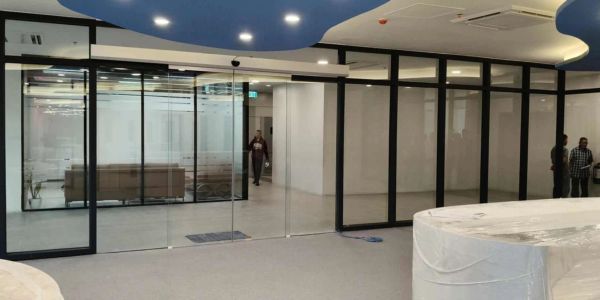 Modern office space with glass walls and a blue ceiling design.
