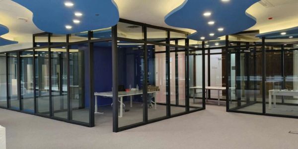 Modern office space with glass partitions and blue ceiling accents.