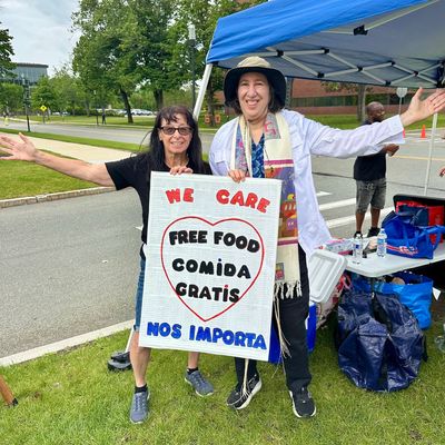 Two people with a sign offering free food in English and Spanish.