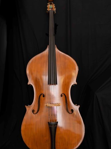 A polished wooden double bass against a black background.