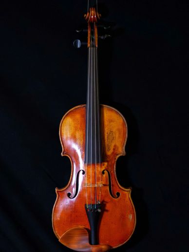 A classic wooden violin with a rich brown finish against a black background.