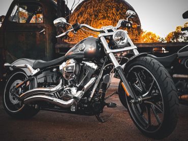 Sleek black motorcycle parked outdoors with autumn foliage in the background.