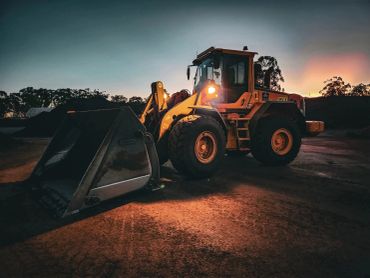 Heavy construction loader vehicle illuminated at sunset.