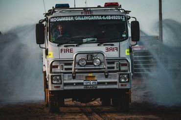 Fire truck moving through smoky terrain with lights on.
