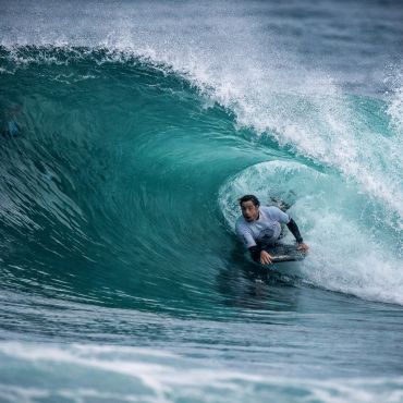 Surfer skillfully rides inside a large turquoise wave barrel.