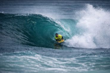 A surfer rides a powerful wave barrel in the ocean.