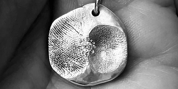 Close-up of a fingerprint pendant with a small embedded gem.