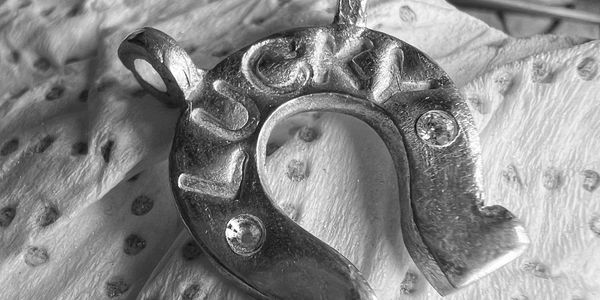 Close-up of a metallic horseshoe pendant with jewels.