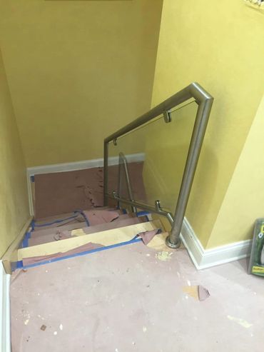 Indoor staircase with glass railing and protective floor covering.