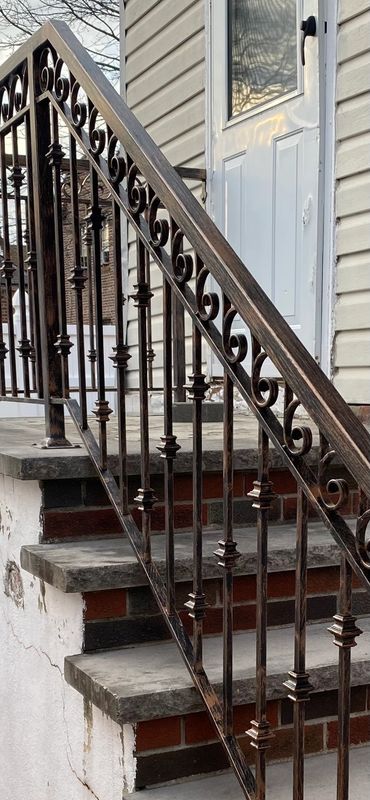 Wrought iron railing on concrete steps leading to a white door.