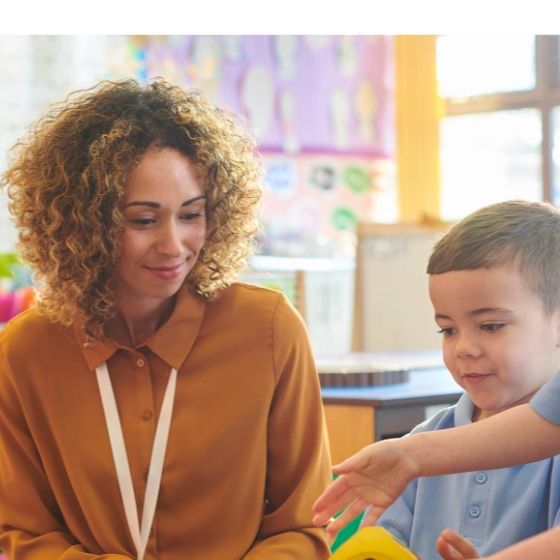 A teacher and young student engaging in a classroom activity together.