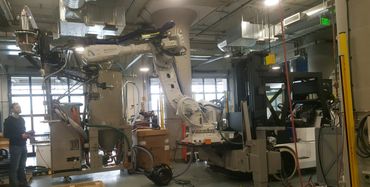 Man operating a large Autodesk robotic arm in an industrial setting.