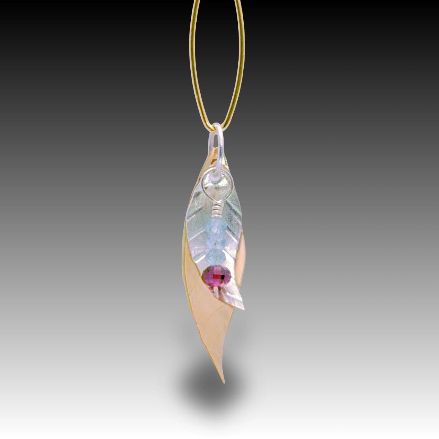 Elegant leaf pendant with colorful beads on a gold chain.