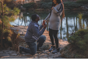 A man proposes to a woman by a serene lakeside.