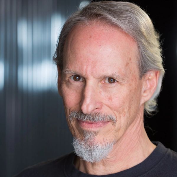 A mature man with a gray beard and intense gaze.