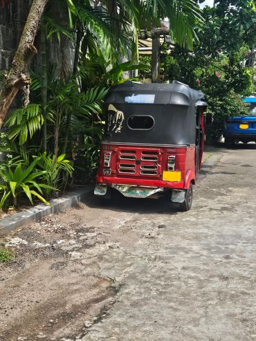 Red tuk-tuk parked on a street