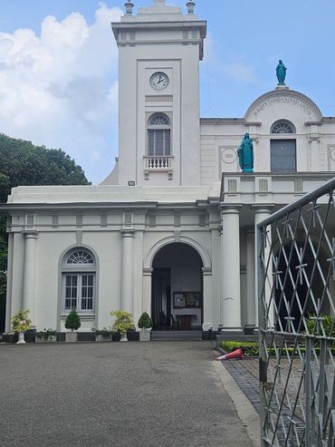 White clock tower building with statues and arched entrance.