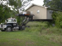 A truck with a crane lifting a small house.
