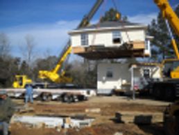 House being lifted by cranes during construction.